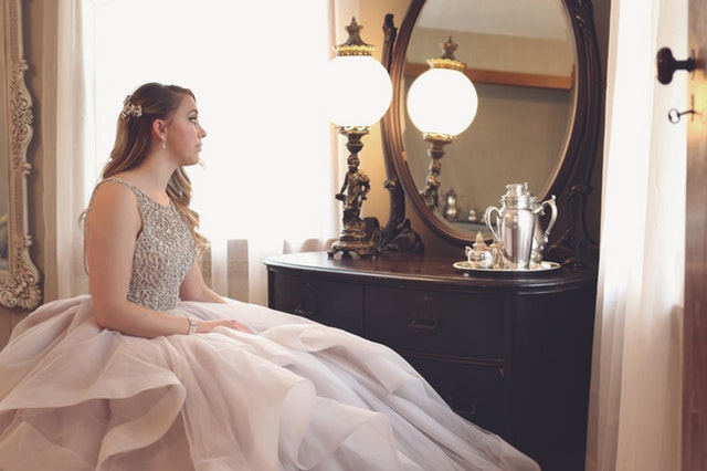 Dívka v nadýchaných šatech sedící před zrcadlem